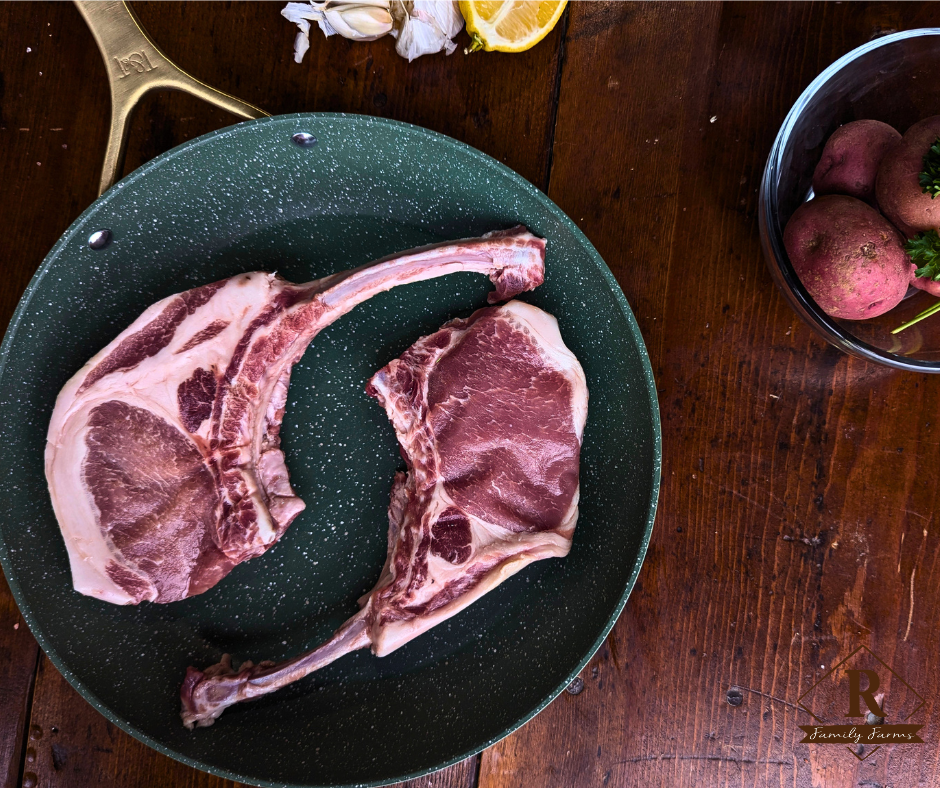 Raw Berkshire pork chops on a black speckled pan with a wooden background