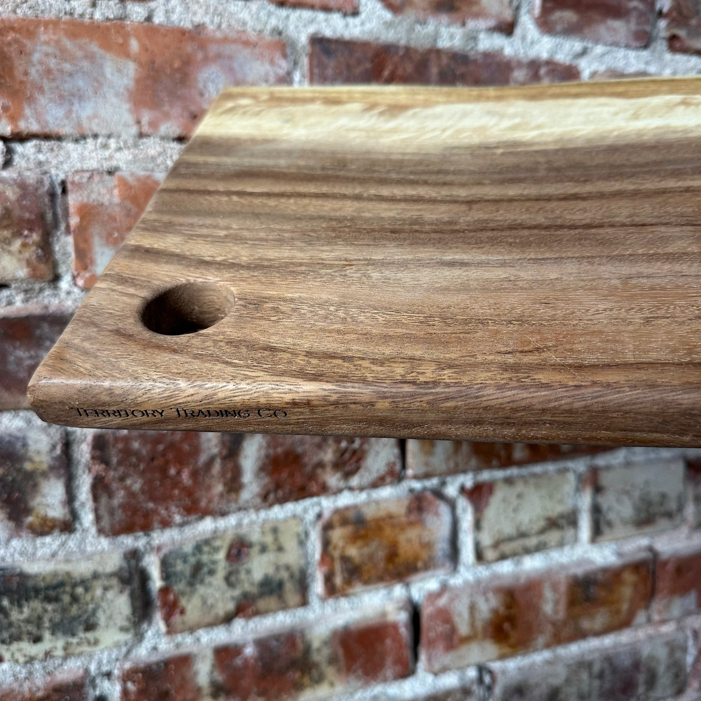 Wooden cutting board with a hole on a brick wall background