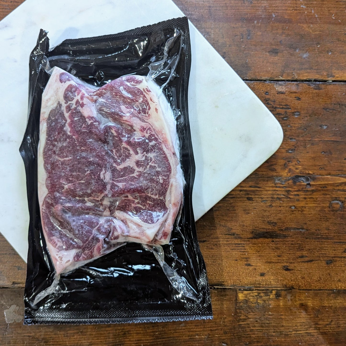 Raw steak in a vacuum-sealed package on a wooden surface