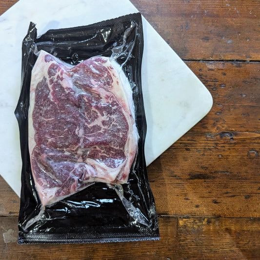 Raw steak in a vacuum-sealed package on a wooden surface